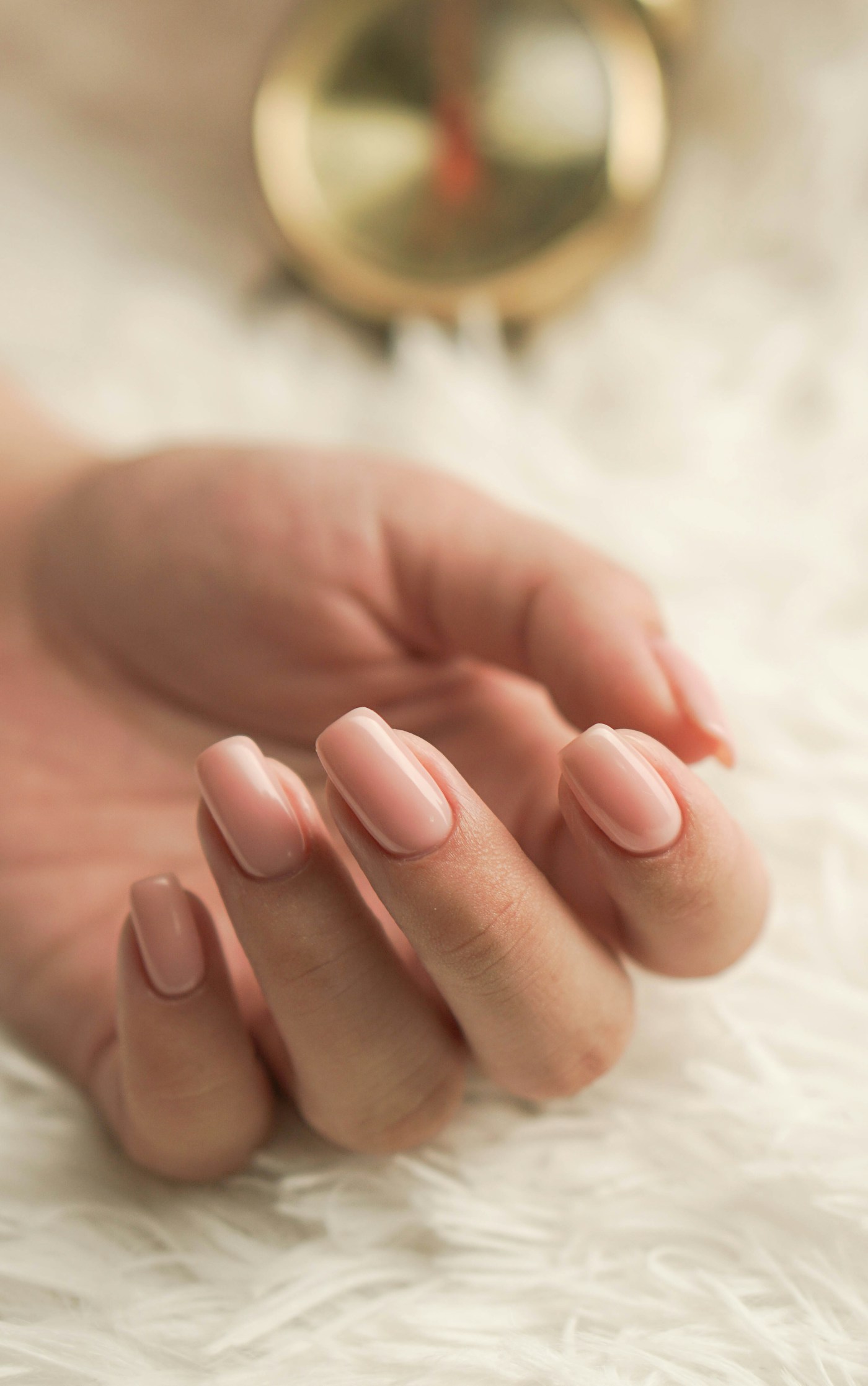 Dłonie z delikatnym mlecznym manicure na jasnym tle — fotografia ilustracyjna